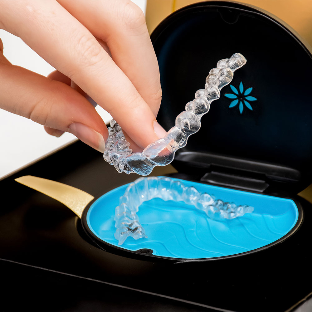 A person is holding up a small, clear plastic tray with a single toothbrush-shaped object inside it.